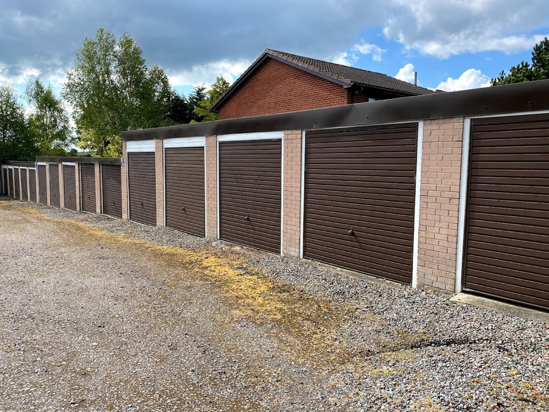 14 lock up garages with brown doors on a slight slope